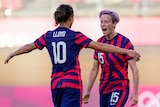 Two women celebrate during a football match at the Olympics.