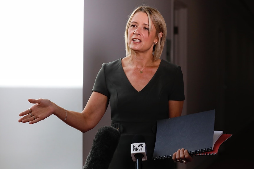 Kristina Keneally holds folders while speaking at a press conference