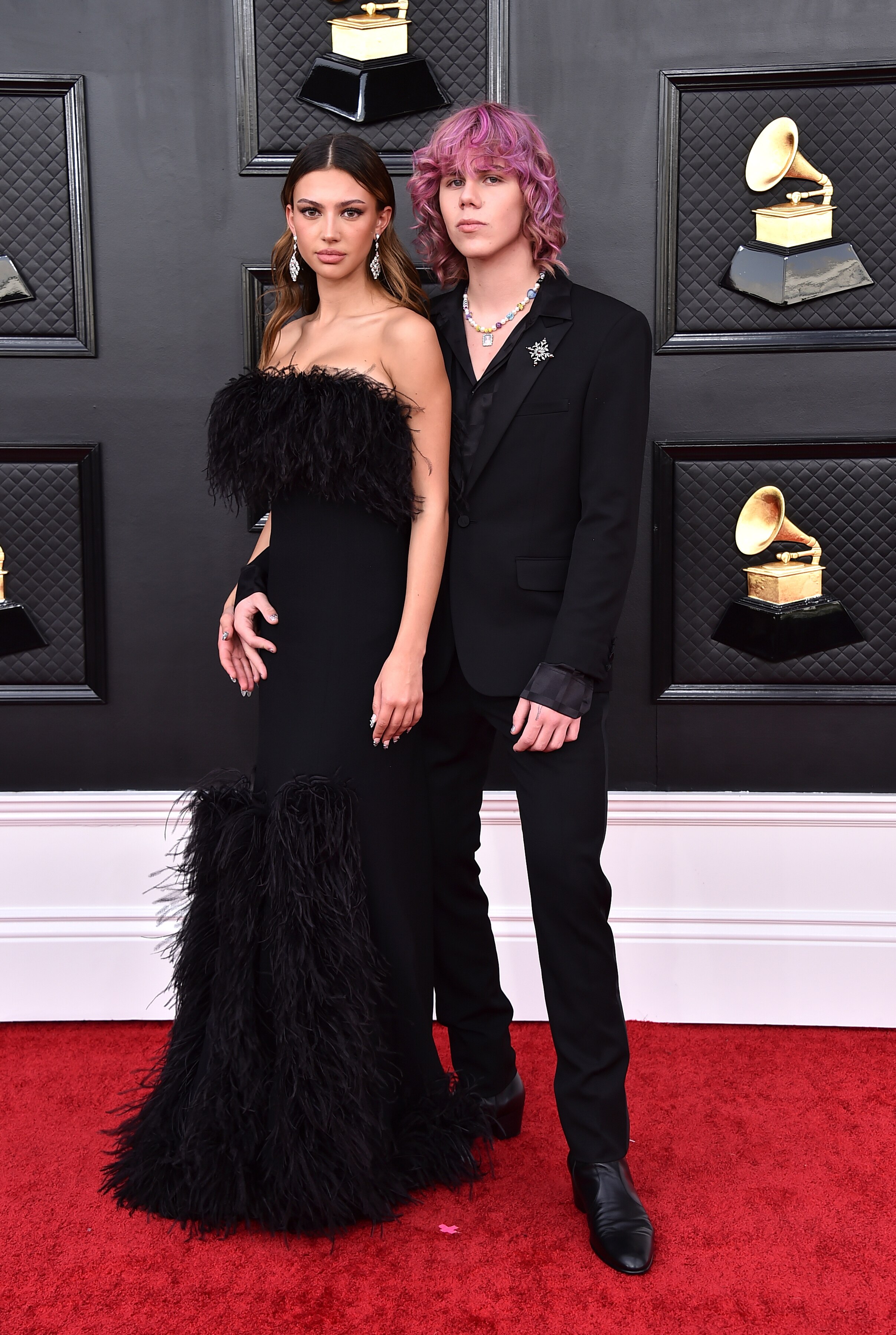 katarina deme in a black dress with feather detail and the kid laroi with pink hair in a black suit
