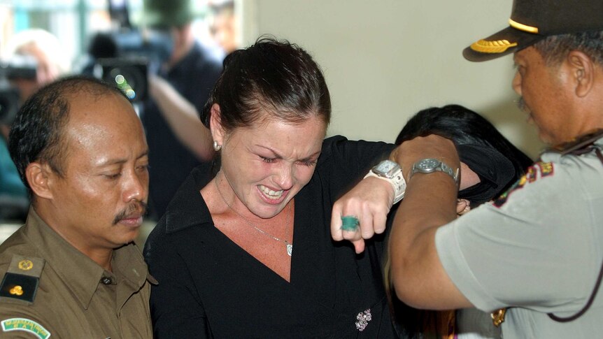 Schapelle Corby resists a police officer attempting to escort her from the court