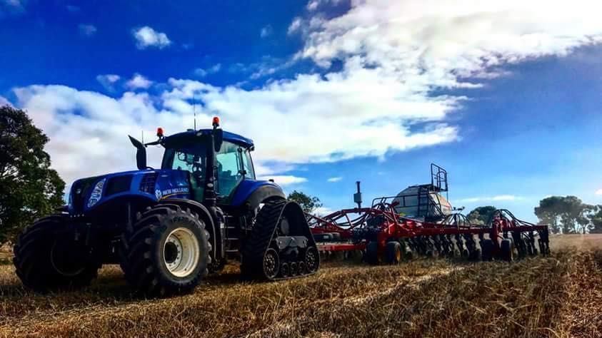 Close up of a blue tractor sowing a crop.