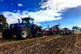 Close up of a blue tractor sowing a crop.