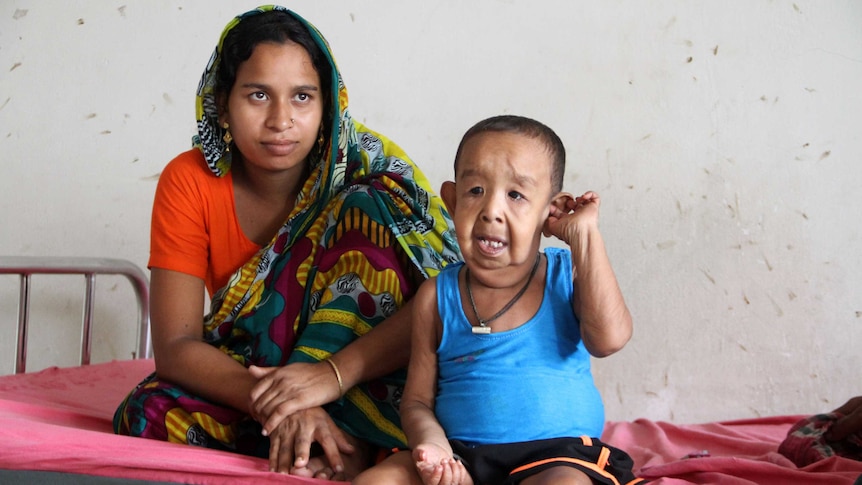 Bayezid Shikdar sits with his mother on a bed at hospital.