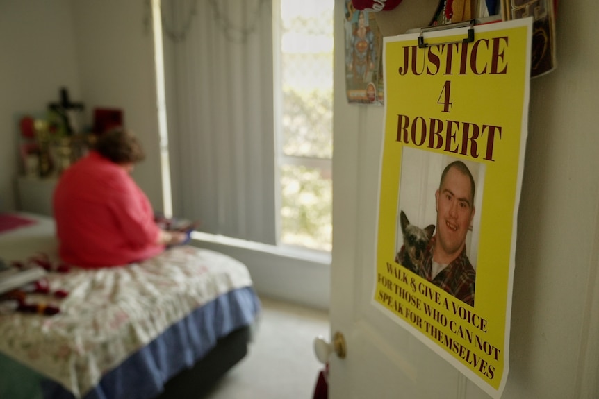 A poster of Robert Tremble hangs on the door while his mum Robyn sits inside the bedroom