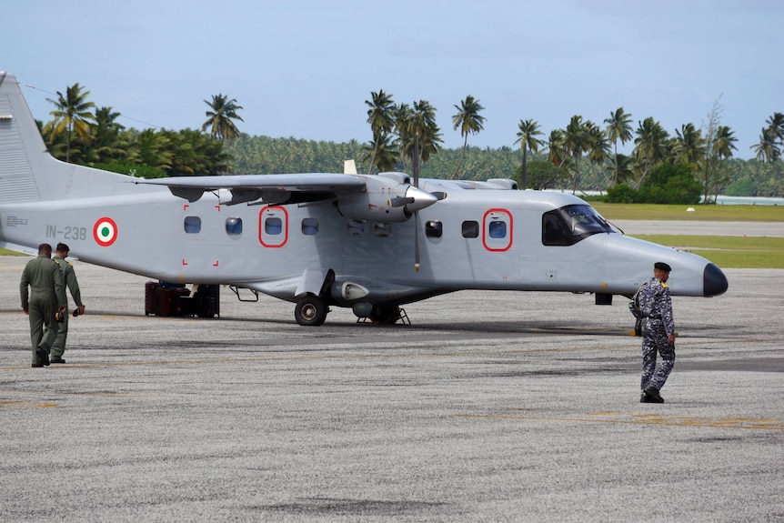 An Indian Air Force Dornier 228 aircraft is parked at the Cocos Island's airfield. Members of the crew 