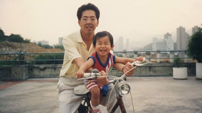 A young boy with his dad on a bicycle