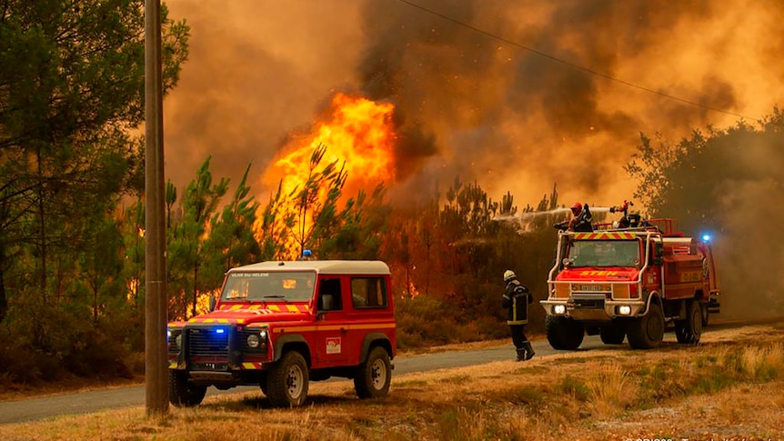 Two fire trucks in front of flames