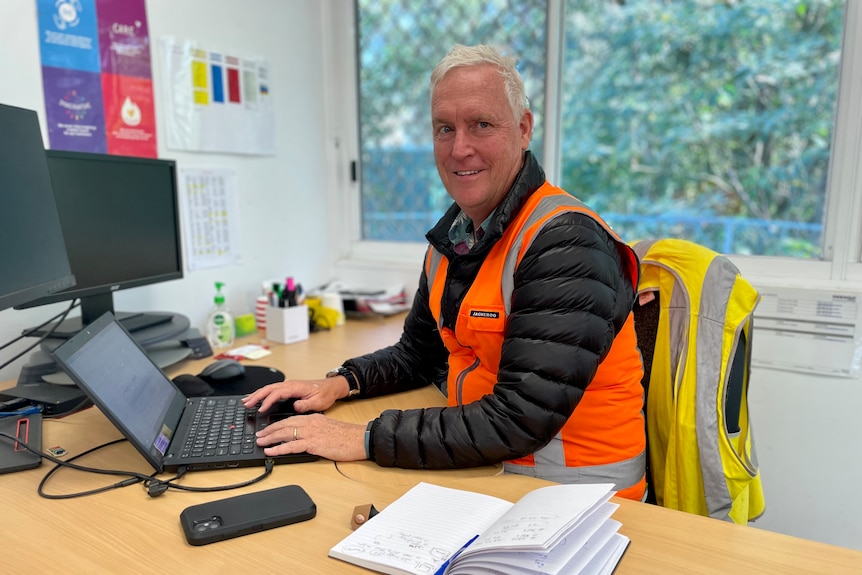 a man in a high-vis vest sitting behind a computer in his office