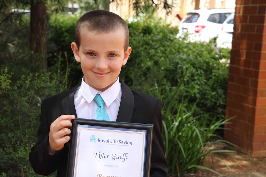 Tyler Guelfi holds up his bravery award at Government House.