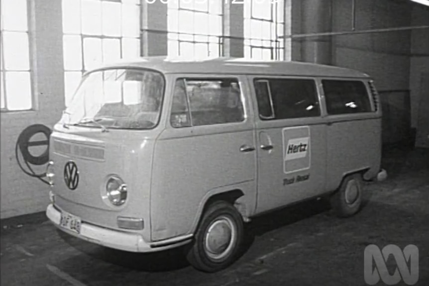A black and white photos of a kombi van parked inside a building