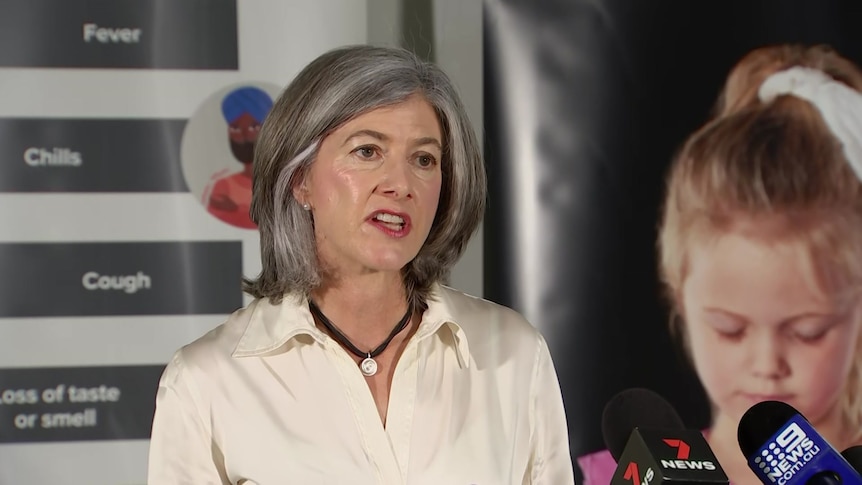 A woman with grey hair wearing a cream shirt