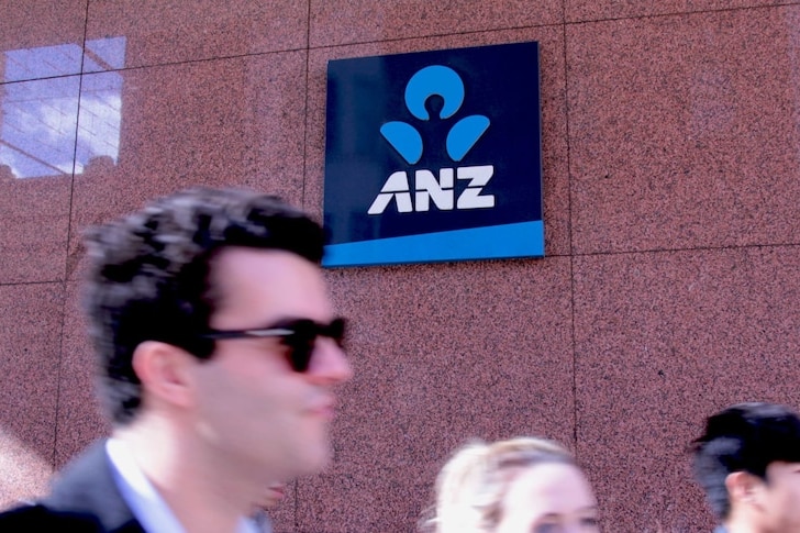 Customers walk past a ANZ logo on the wall of a bank in Sydney.