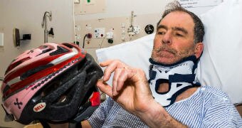 Peter Gee shows the helmet which saved his life from his hospital bed in tasmania