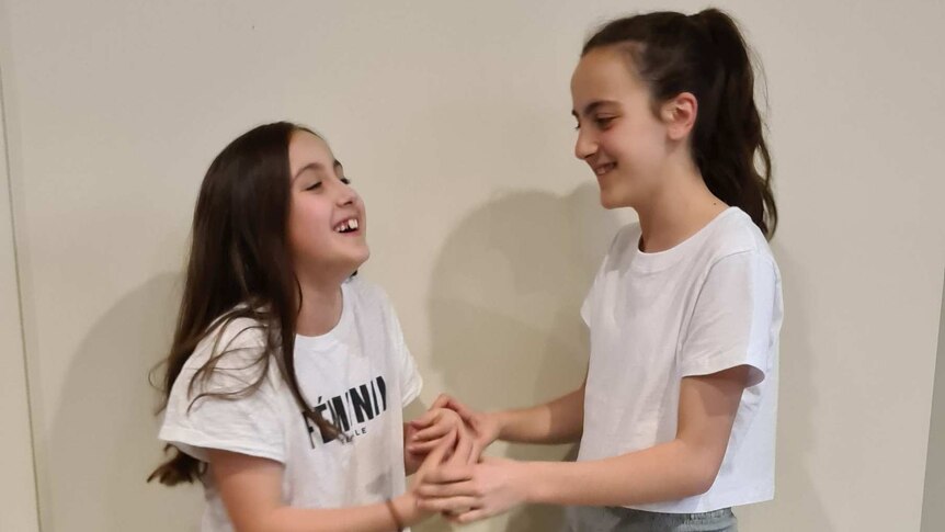 Two girls laughing with each other.
