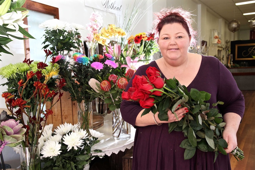 Florist Renay Horton stands in her shop holding a bouquet of flowers.