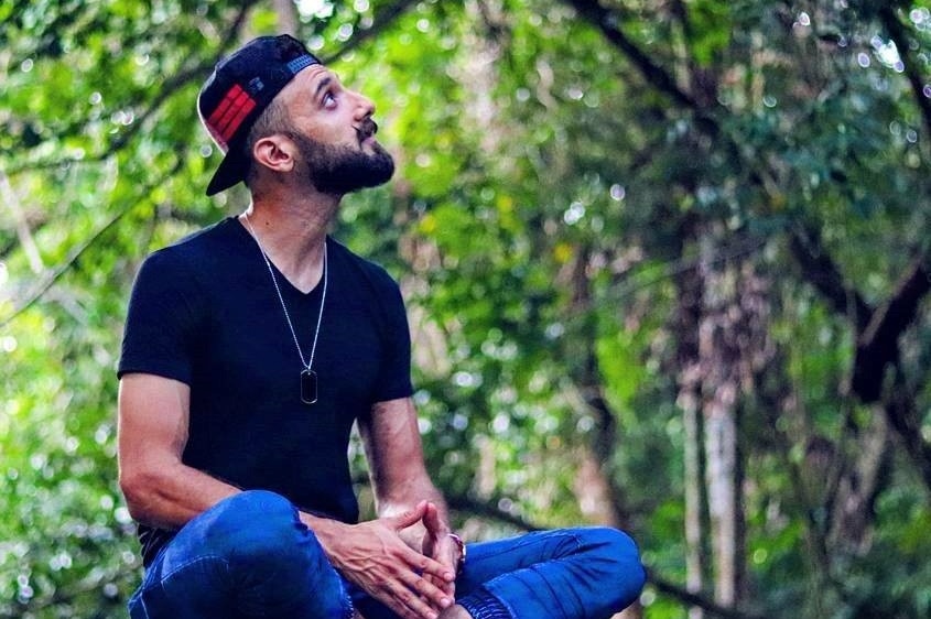 Zohab Khan sitting cross-legged on a rock looking upwards for a story about rudeness and stress telemarketers experience.