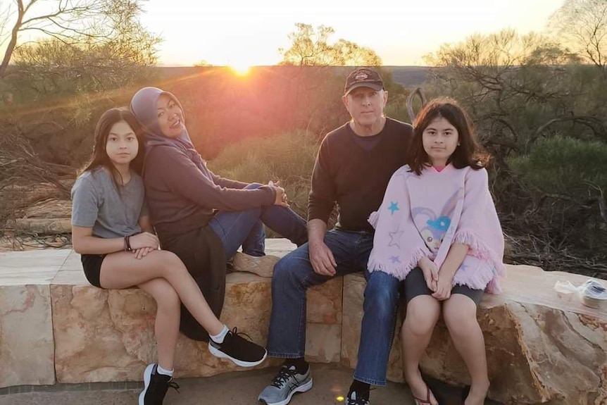 A man, women and their daughters sitting outdoor.