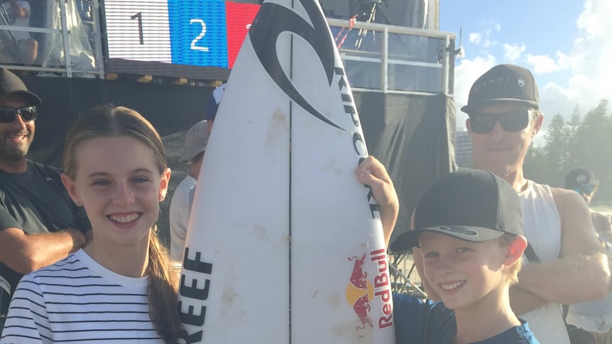 [Nate Johnson poses with his sister Jess and the surfboard gifted by Mick Fanning]