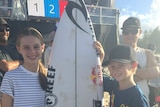 [Nate Johnson poses with his sister Jess and the surfboard gifted by Mick Fanning]