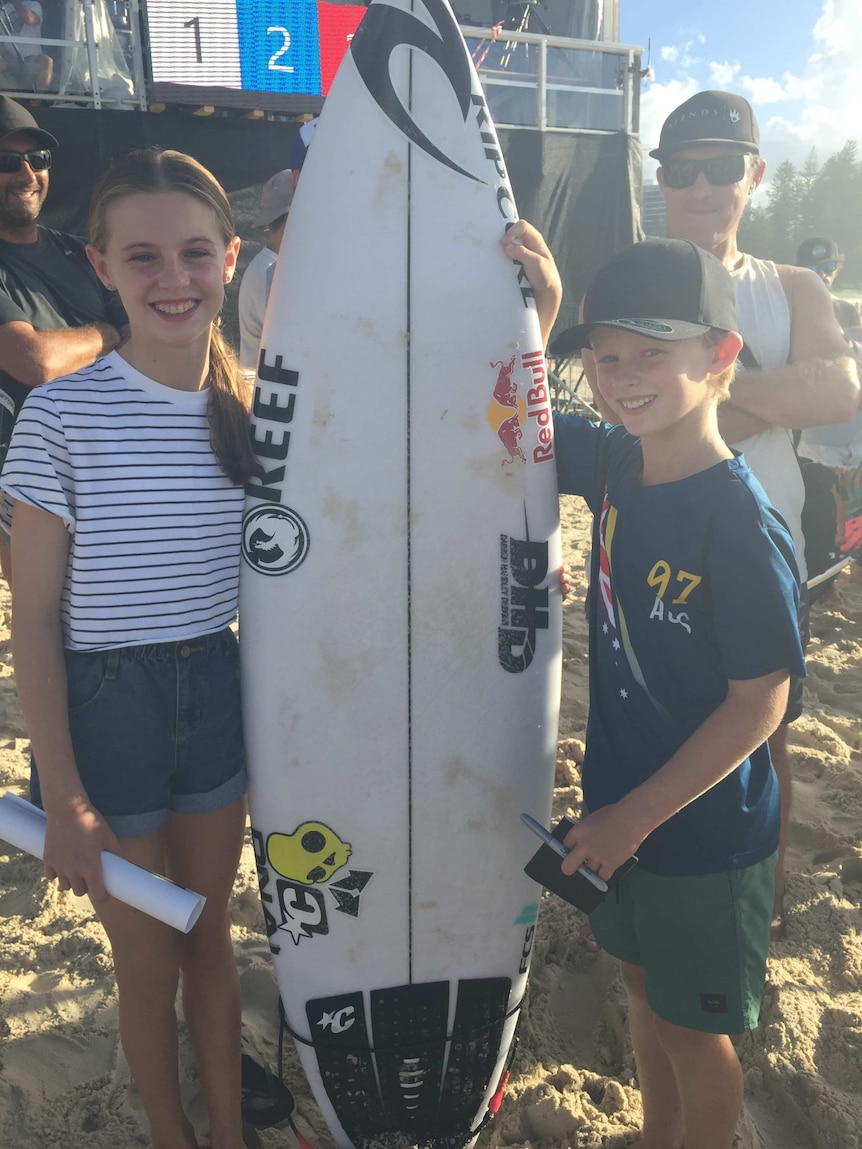 [Nate Johnson poses with his sister Jess and the surfboard gifted by Mick Fanning]