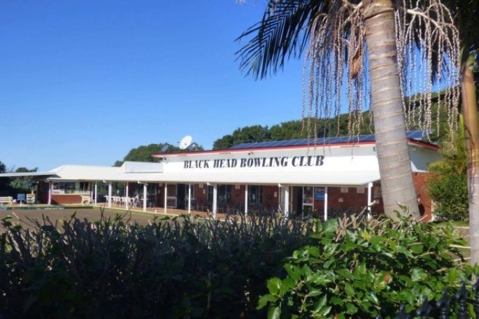 An exterior view of a bowling club, with shrubs in the foreground.