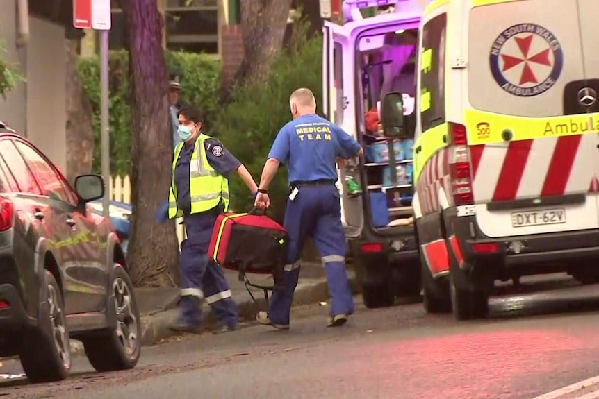 Paramedics carry bags away from an ambulance.