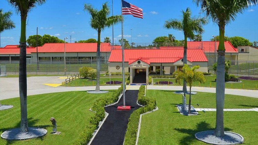A picture of the jail where fraudster Jack Utsick is imprisoned, there is an American flag waving on a green lawn outside.