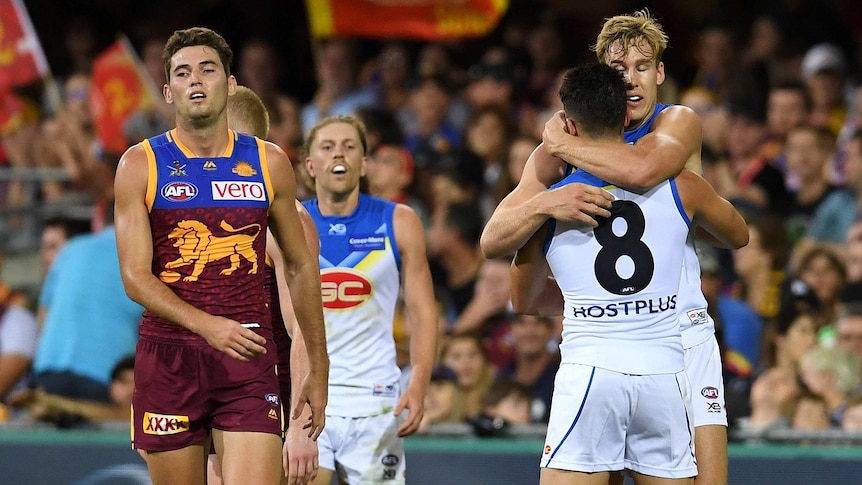 Tom Lynch of the Suns (R) hugs teammate Brayden Fiorini after a goal against the Lions at the Gabba.