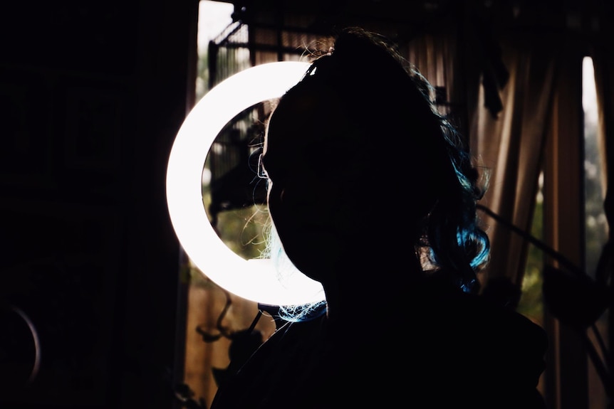 The shadow of a woman's face, with curtains in the background.