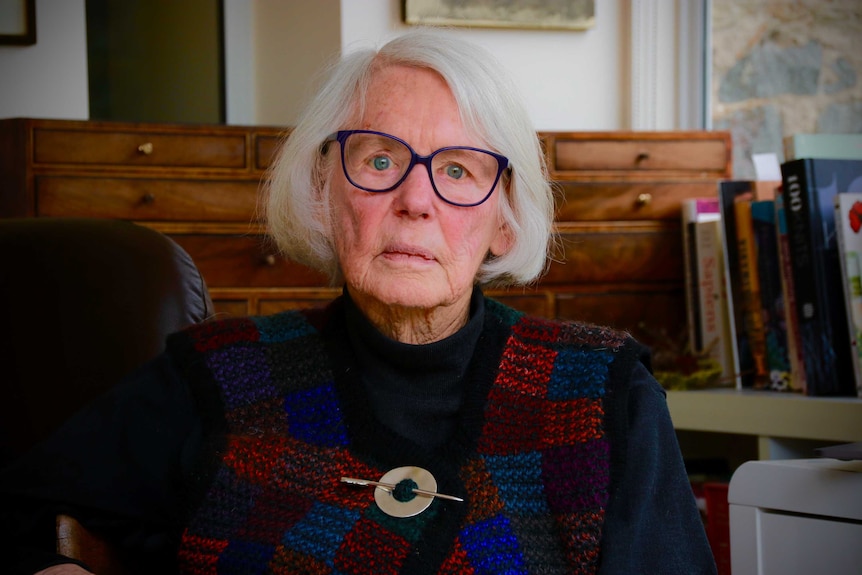 An older woman with a short grey bobbed haircut and large-rimmed eyeglasses.