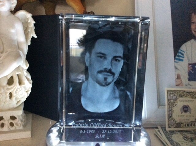 A blue tones framed photo of a man witha goatee. 