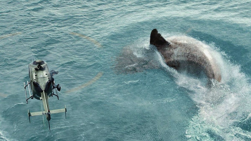 A helicopter hovers over a massive shark in a still from the film.