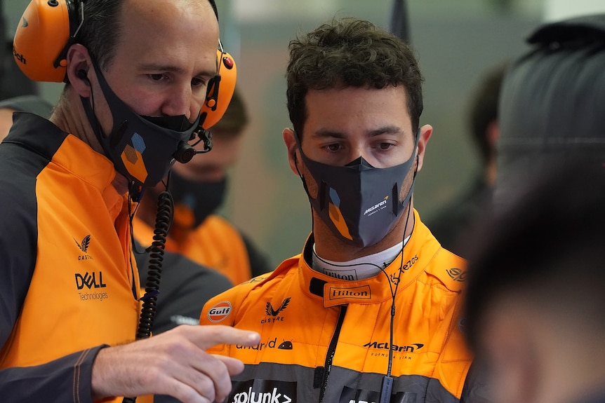 Race driver with a mechanic discussing their car in a garage. 