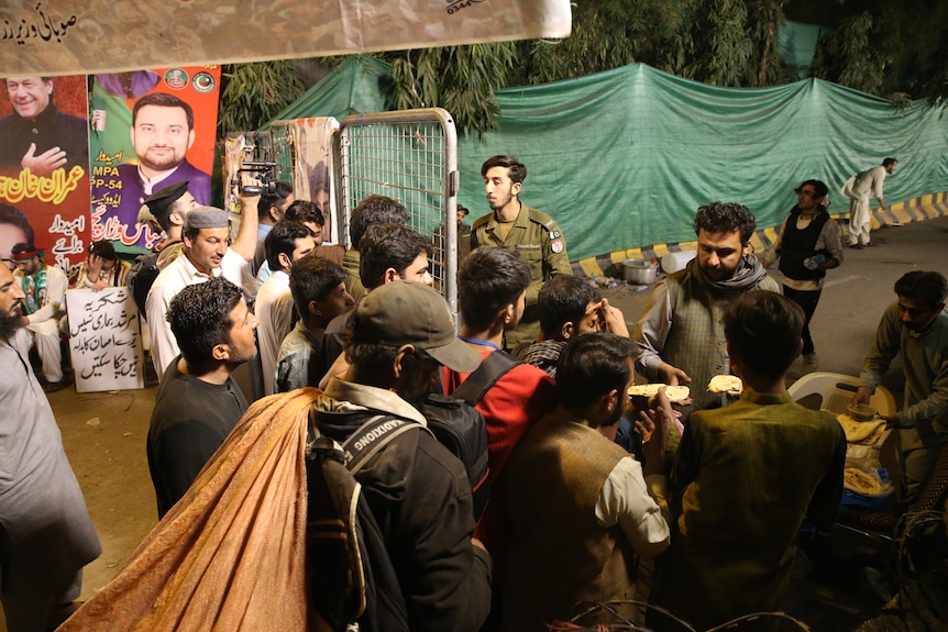 Supporters of Pakistan's former Prime Minister Imran Khan wait outside his house in Lahore.