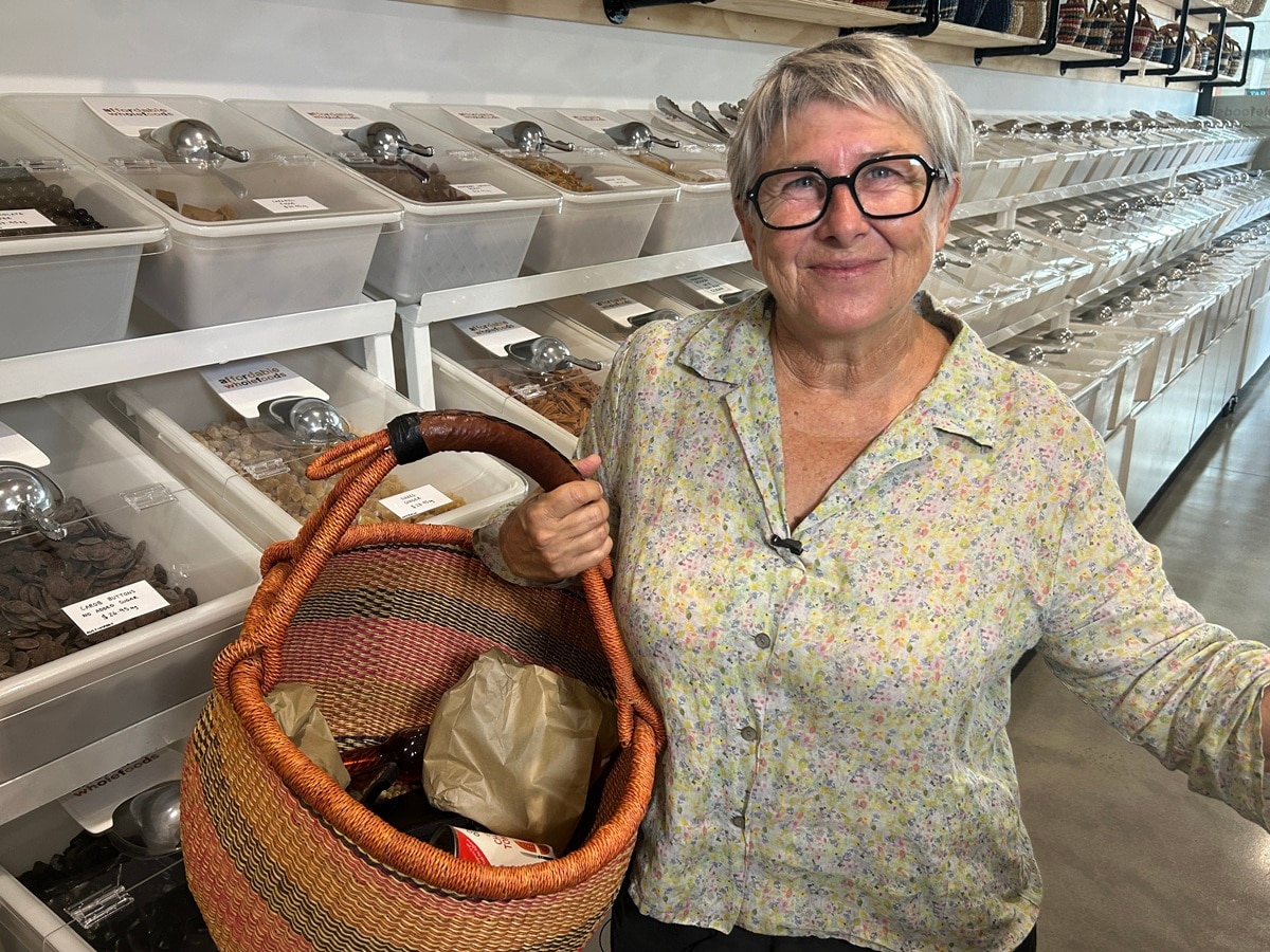 Mulher com cesto de compras em armazém de alimentos a granel.