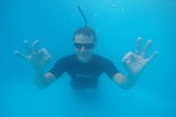 Dmitriy Ross underwater giving the ok sign with both hands while freediving