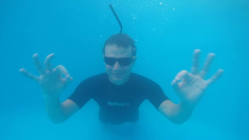 Dmitriy Ross underwater giving the ok sign with both hands while freediving
