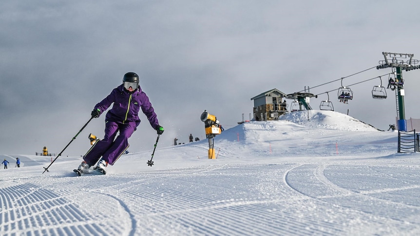 A skier wearing a purple outfit makes their way across the snow.