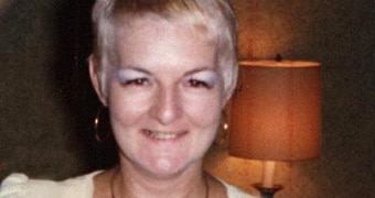 A tight head and shoulders shot of Shirley Finn in a white dress smiling for the camera.