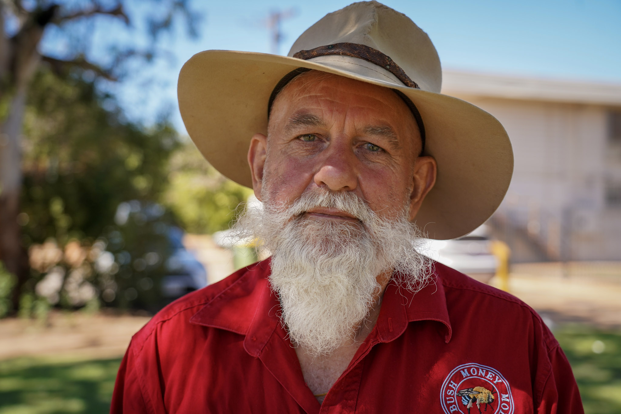 Un hombre con barba blanca y sombrero de ala ancha mira a la cámara.