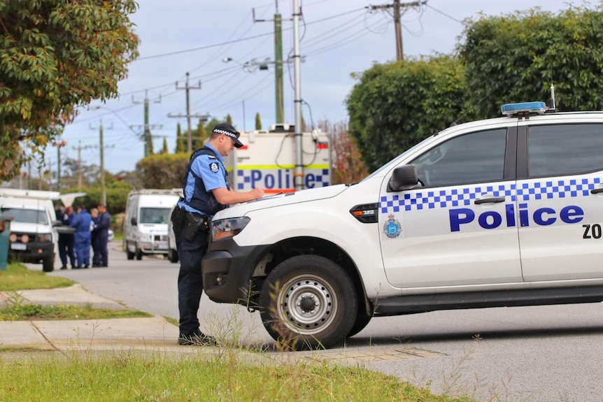 A police officer at a road block on a suburban street.