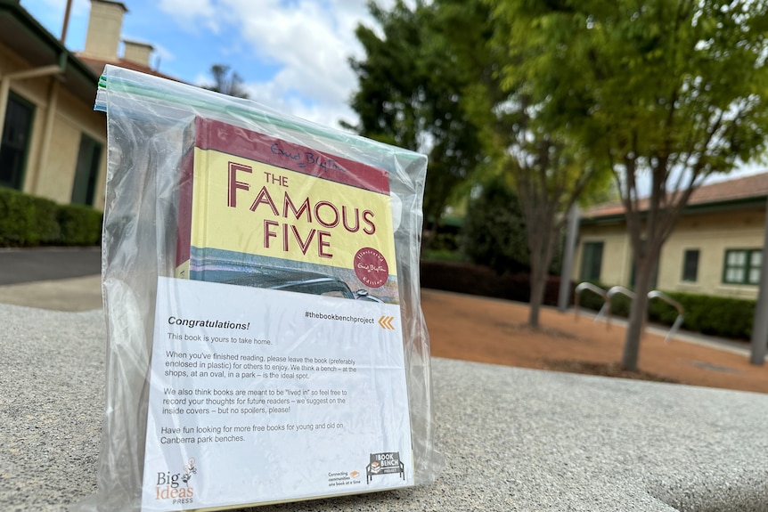 A book titled The Famous Five with a post card in front saying Congratulations. 