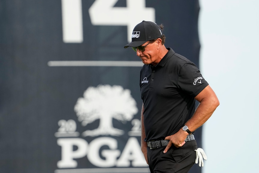 Phil Mickelson looks down with his hand on his hip