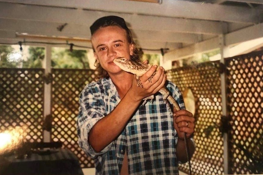 Adrian Trett smiles at the camera while holding a lizard