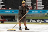 Curator sweeps water off Manuka Oval