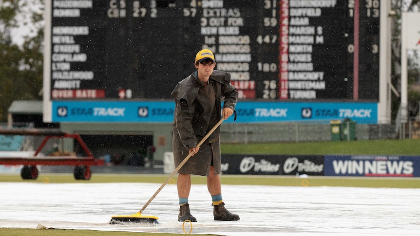 Curator sweeps water off Manuka Oval