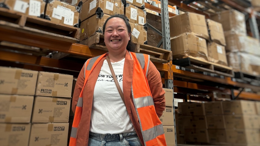 Debbie Hatumale-Uy standing in front of boxes stacked in a warehouse.