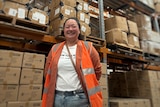 Debbie Hatumale-Uy standing in front of boxes stacked in a warehouse.