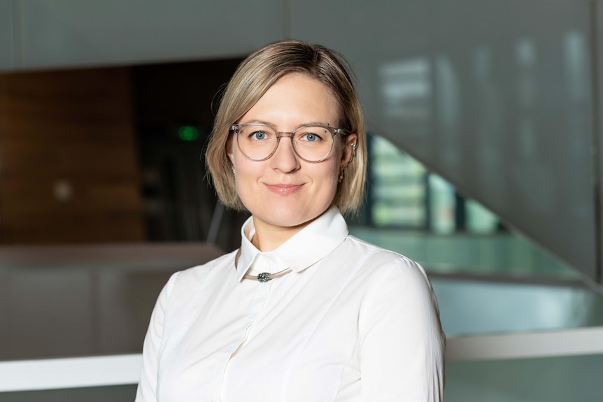 A woman wearing glasses smiles for a portrait