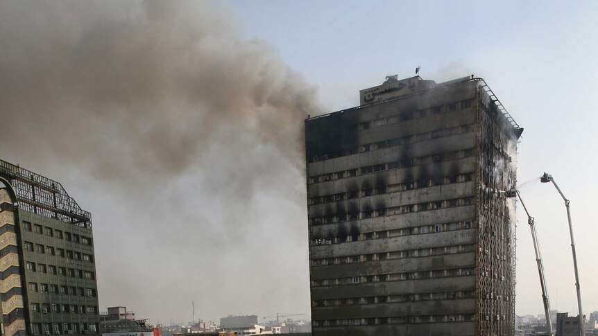 Smoke rises up from the Plasco building where firefighters work to extinguish a fire in central Tehran